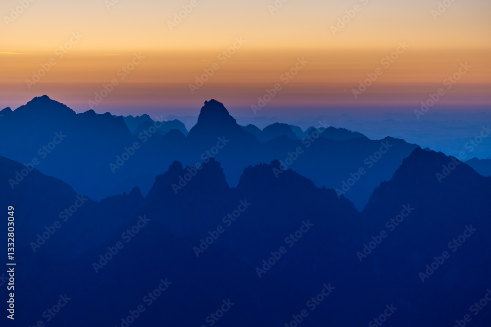 Obraz premium Sunset silhouette of the mountains in the Alps. Dolomites alpine beautiful landscape in red, orange and yellow light of sunset and sunrise, dawn soft light through darkness of the sky in the Dolomiti