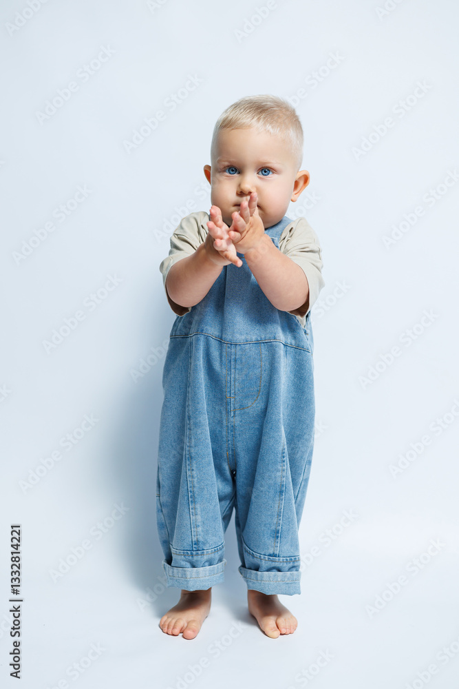 Adorable and Cute Toddler Dressed in Denim Overalls Making a Playful Gesture of Joy