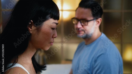 Breakup relationship interracial couple in bedroom, disappointed Japanese woman feels betrayed and cheated because of her husband's adultery. Caucasian man apologizes to his wife after an argument.