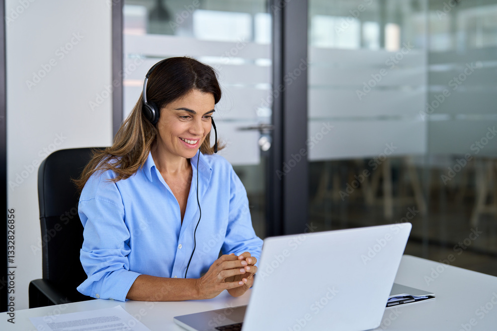 Smiling middle aged senior female operator wearing headset working using laptop computer in office. Busy mature business woman call centre representative customer support agent talking to client. Smiling middle aged senior female operator wearing headset working using laptop computer in office. Busy mature business woman call centre representative customer support agent talking to client.