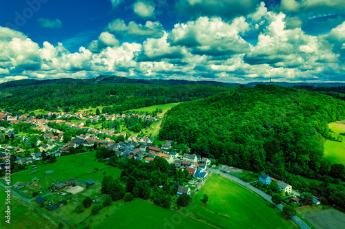Obraz na płótnie Vibrant German Village Nestled in a Valley Surrounded by Lush Greenery and Picturesque Mountains on a Bright Sunny Day w salonie