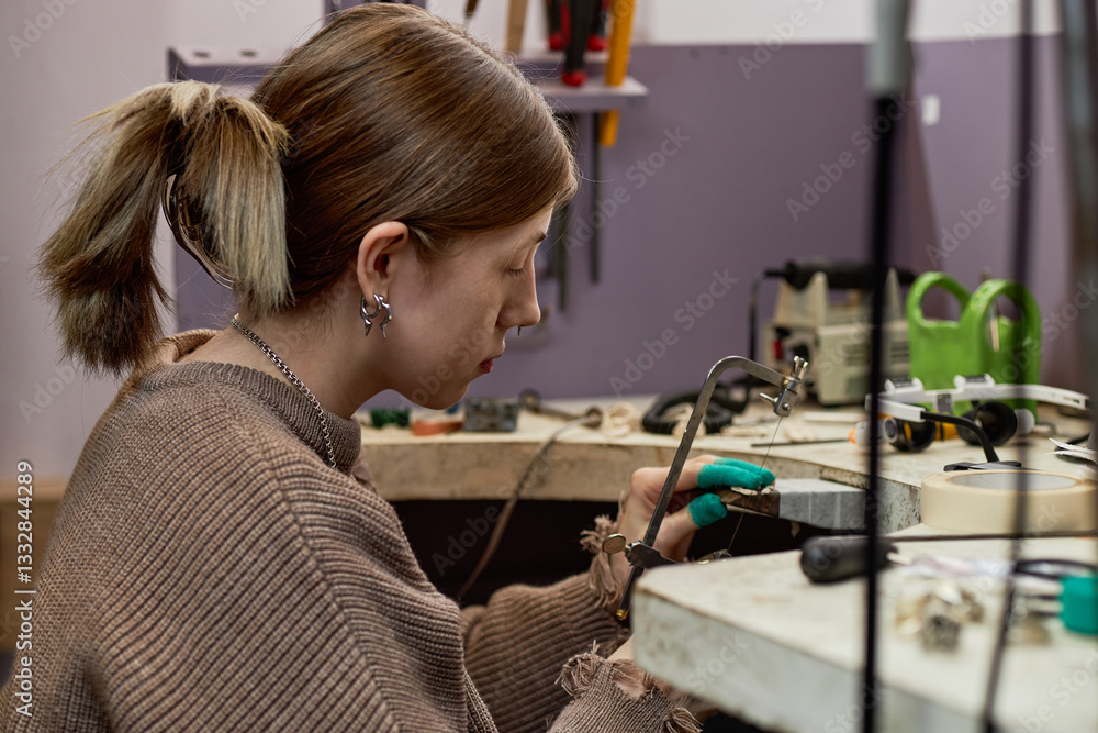 Young female artisan working meticulously on a small object using precision tools in workshop, surrounded by various equipment and gadgets Young female artisan working meticulously on a small object using precision tools in workshop, surrounded by various equipment and gadgets