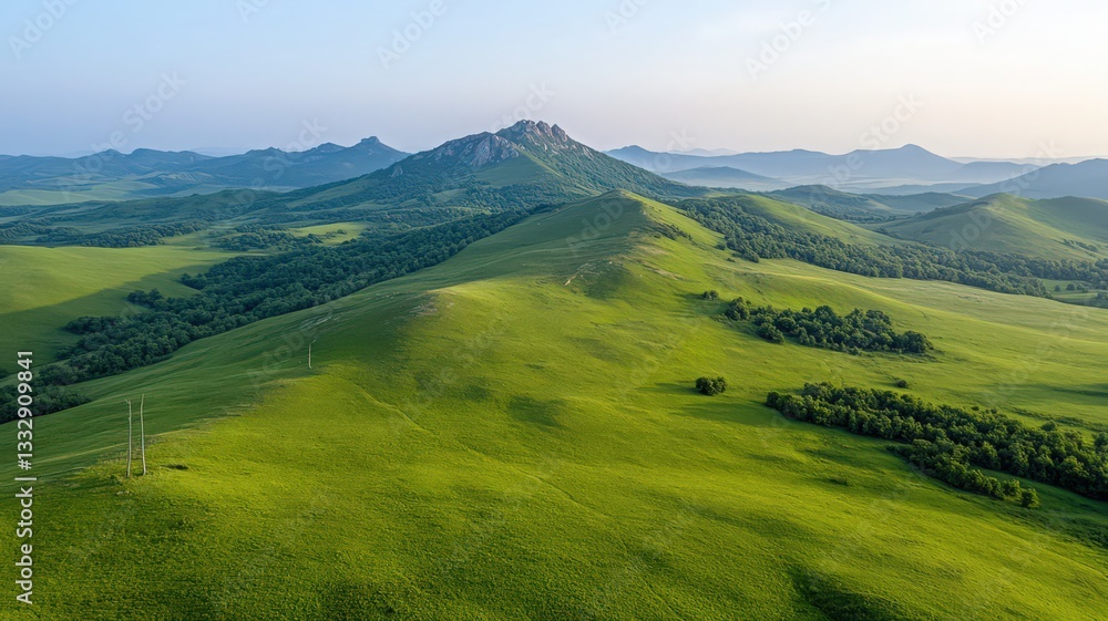 Obraz premium Aerial View of Rolling Green Hills and Mountains Under a Clear Sky