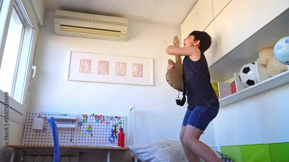 Elementary age boy rocking out in his bedroom, dancing and singing with a cool recycled electric guitar Elementary age boy rocking out in his bedroom, dancing and singing with a cool recycled electric guitar