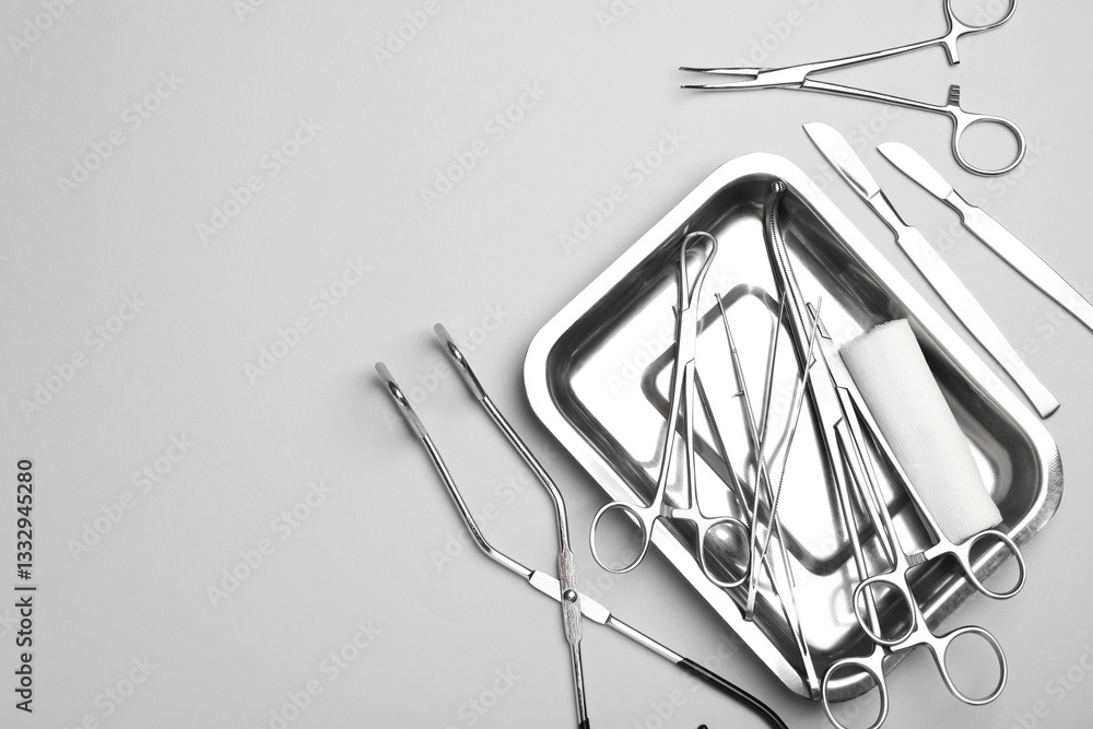 Fototapeta premium Different surgical tools on light gray background, flat lay. Space for text