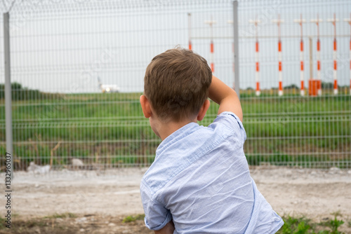 Wallpaper Mural A young boy sheds tears as an airplane departs behind a fence at an airport. Ideal for showcasing heartfelt goodbyes and the emotional side of travel with kids. Torontodigital.ca