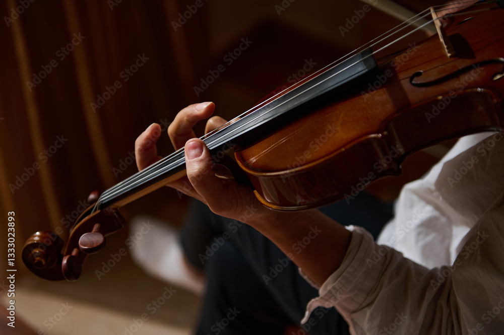 Close-up of a violinist playing a violin with focused skill Close-up of a violinist playing a violin with focused skill