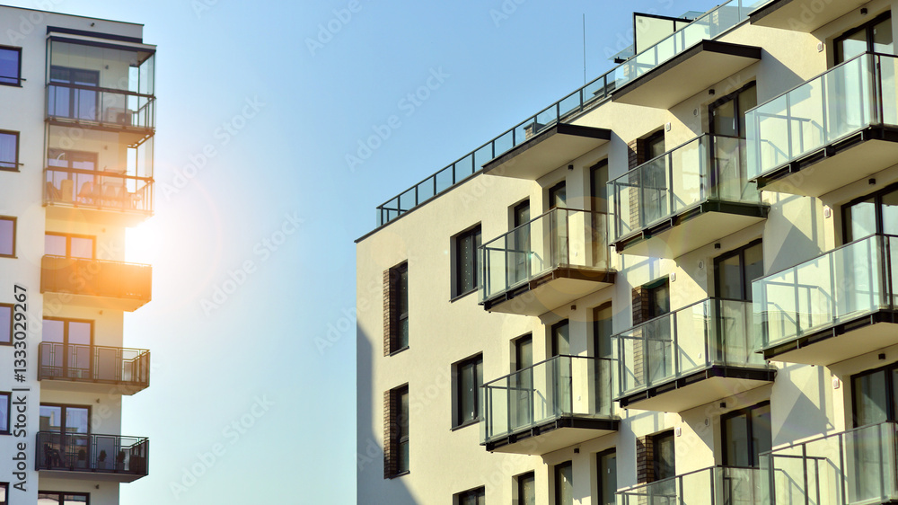 Obraz premium Apartment building with symmetrical modern architecture in the city. Modern apartment building on a sunny day. Facade of a modern apartment building. Bottom view. 