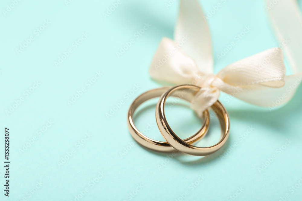 Wedding rings tied with ribbon on light blue background, closeup. Space for text Wedding rings tied with ribbon on light blue background, closeup. Space for text