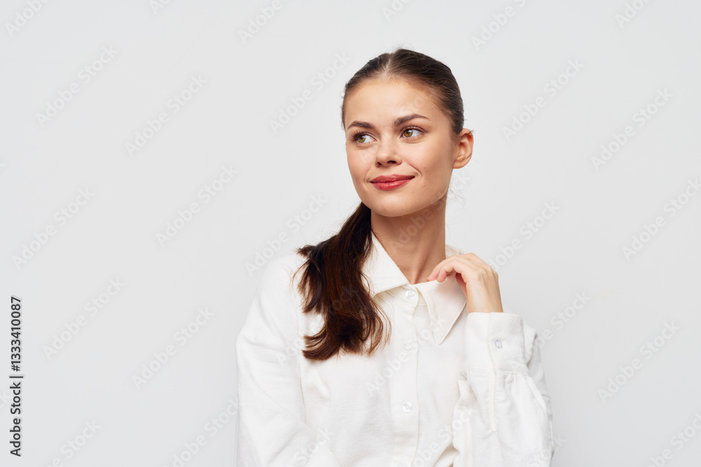 Young woman with a cheerful expression, wearing a white shirt against a plain light background, exuding confidence and positivity Her hairstyle is a simple ponytail Young woman with a cheerful expression, wearing a white shirt against a plain light background, exuding confidence and positivity Her hairstyle is a simple ponytail