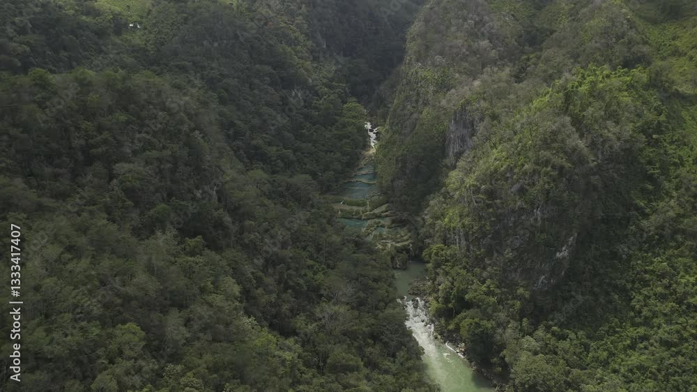 Drone flies up and away from the Semuc Champey National Park and follows the Cahabon River north on partially cloudy afternoon in Guatemala Drone flies up and away from the Semuc Champey National Park and follows the Cahabon River north on partially cloudy afternoon in Guatemala