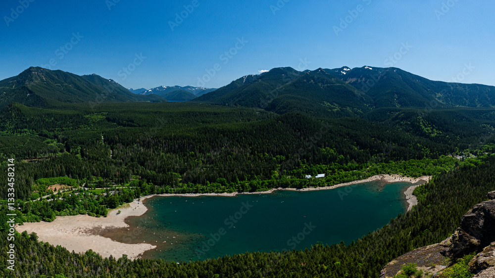 Fototapeta premium An aerial panorama capturing a serene mountain lake surrounded by lush greenery and majestic peaks highlights the breathtaking beauty of nature's untouched landscapes.