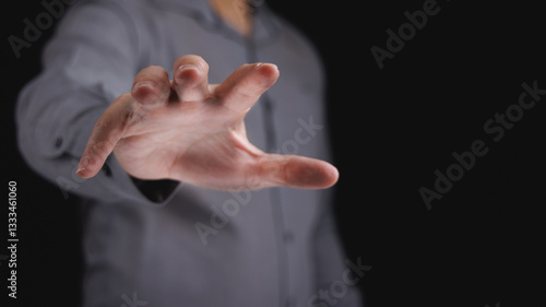 Quadro em tela Businessman hand reach out to grab something in black background in concept of seize for opportunity and success