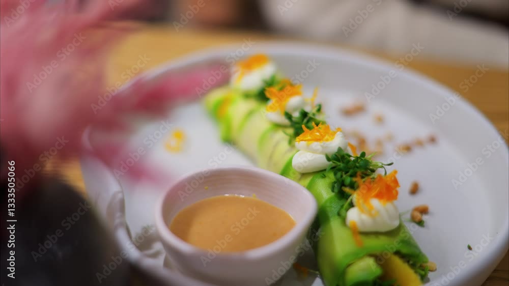 Close up of an avocado roll with sauce on a white plate at a restaurant Close up of an avocado roll with sauce on a white plate at a restaurant