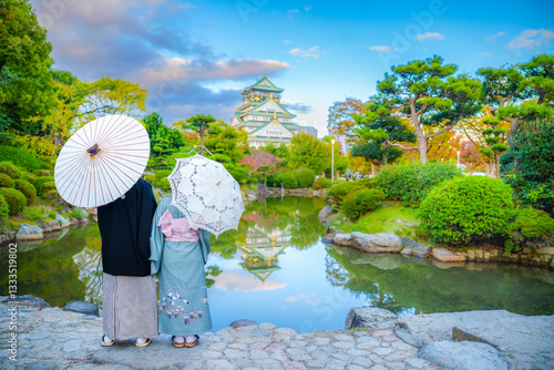 Asain couple lover man and woman wear kimono japanese traditional standing and looking landscape view Osaka Castle at sunset sky in Autumn, Osaka, Japan.
