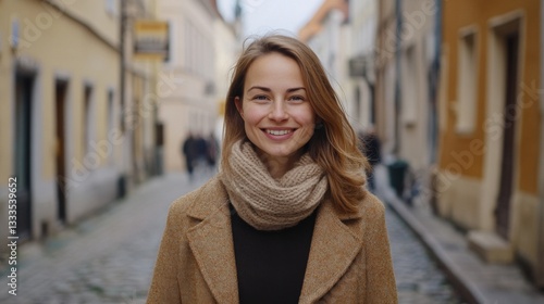 Smiling woman in a brown coat stands on a cobblestone street