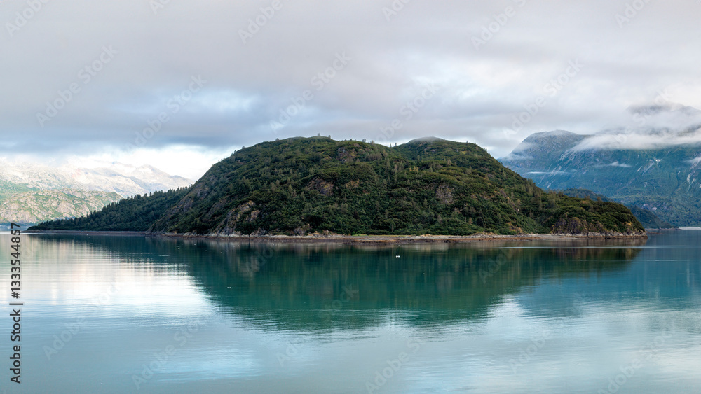 An elegant island covered in rich greenery stands proudly in calm waters, perfectly mirrored, illustrating the beauty of nature's reflections and the allure of untouched landscapes. An elegant island covered in rich greenery stands proudly in calm waters, perfectly mirrored, illustrating the beauty of nature's reflections and the allure of untouched landscapes.
