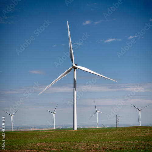 A stunning view of modern wind turbines standing tall against a bright blue sky, symbolizing sustainable energy and the advancement of green technology.
