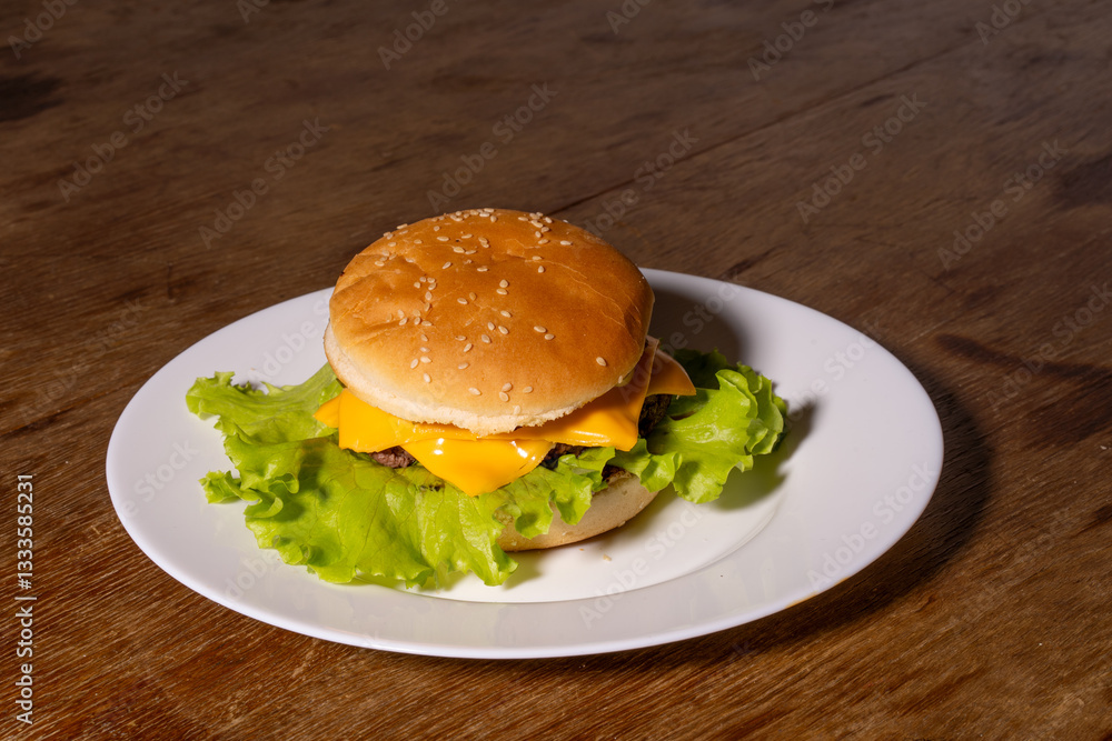 A juicy cheeseburger with a sesame seed bun, melted cheese, beef patty, and lettuce on a white plate, styled atop a rustic wooden background.