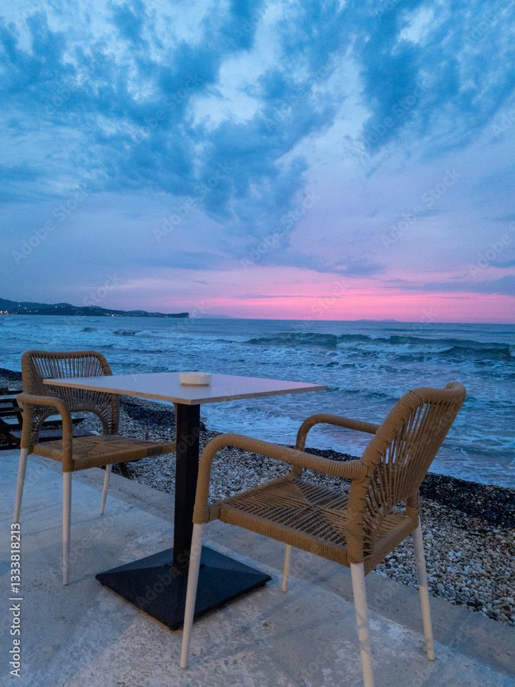 Seaside table with two chairs presents a serene beachside scenery during the calming dusk hours. Seaside table with two chairs presents a serene beachside scenery during the calming dusk hours.