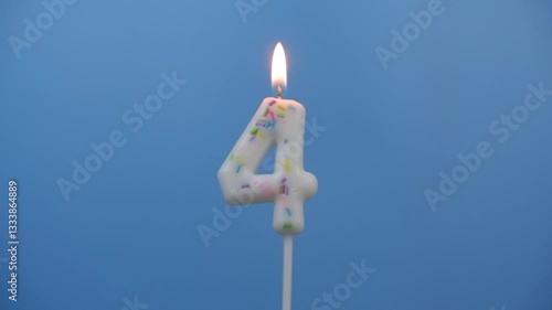 Burning white birthday candle on blue background, number 4.	