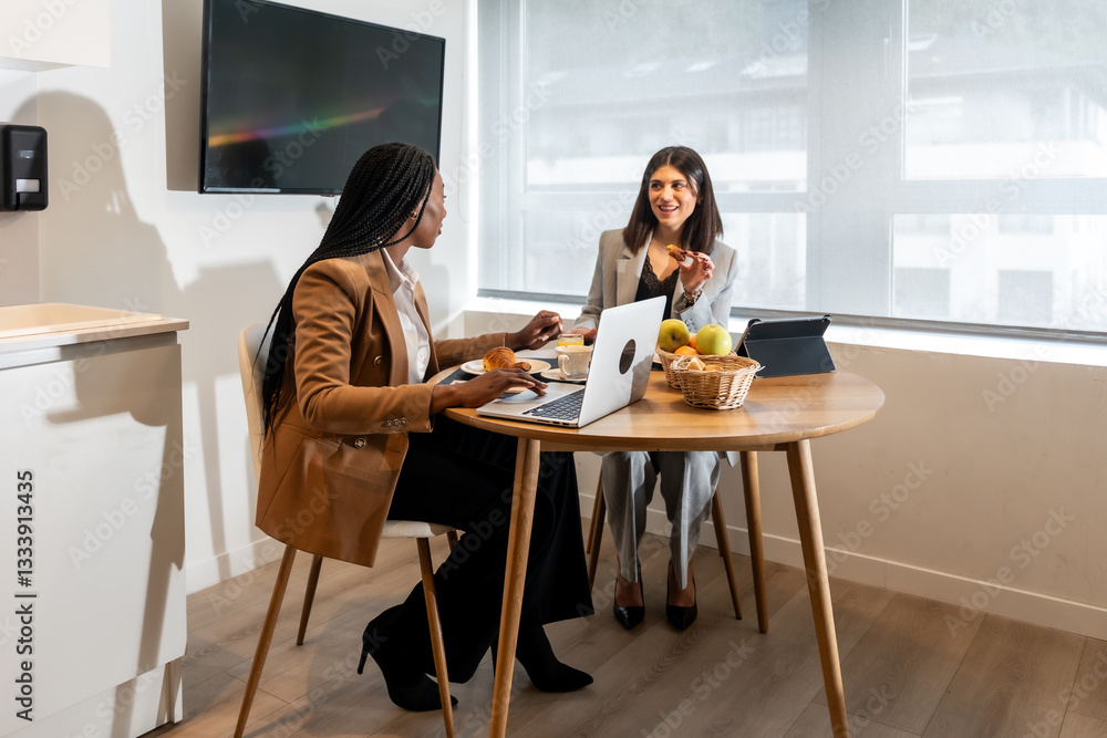 Businesswomen having breakfast and working on a laptop in hotel room Businesswomen having breakfast and working on a laptop in hotel room