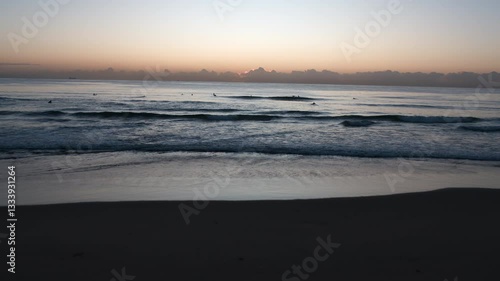 Wallpaper Mural  Aerial Dawn Over the Coast: Rolling Waves, Surfers, and the Sun Emerging from Behind Clouds on the Horizon. Torontodigital.ca