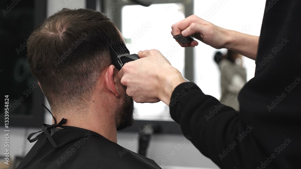 Skilled barber trimming client's hair using electric razor, creating contemporary hairstyle in modern barbershop setting with precise, professional technique