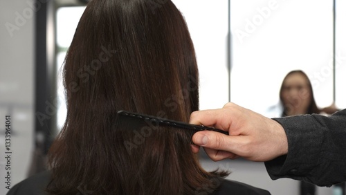Obraz na płótnie Professional hairdresser carefully combing sleek brown hair, working precisely within bright modern salon setting, preparing for transformative styling session w salonie