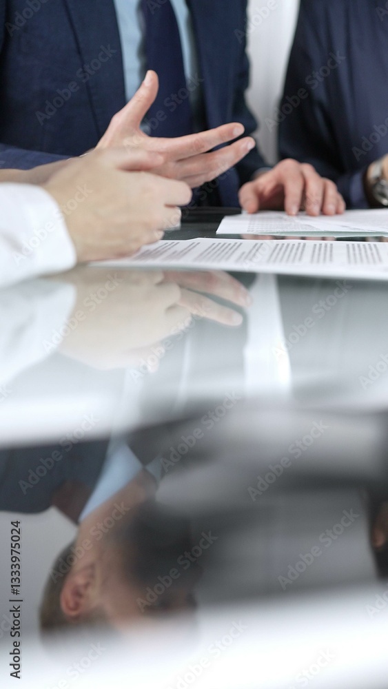 Business people are discussing a contract during meeting while sitting at the glass table in office, vertical close up view. Concept of success and team work