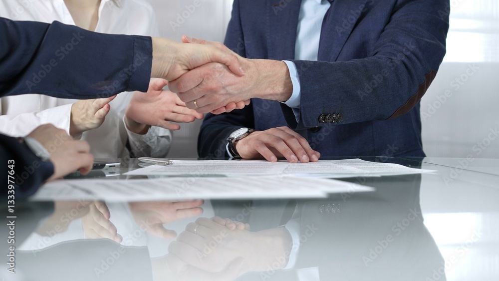 Unrecognizable business partners shaking hands after signing contract at glass table in office meeting, making a deal and closing agreement, close up of handshake