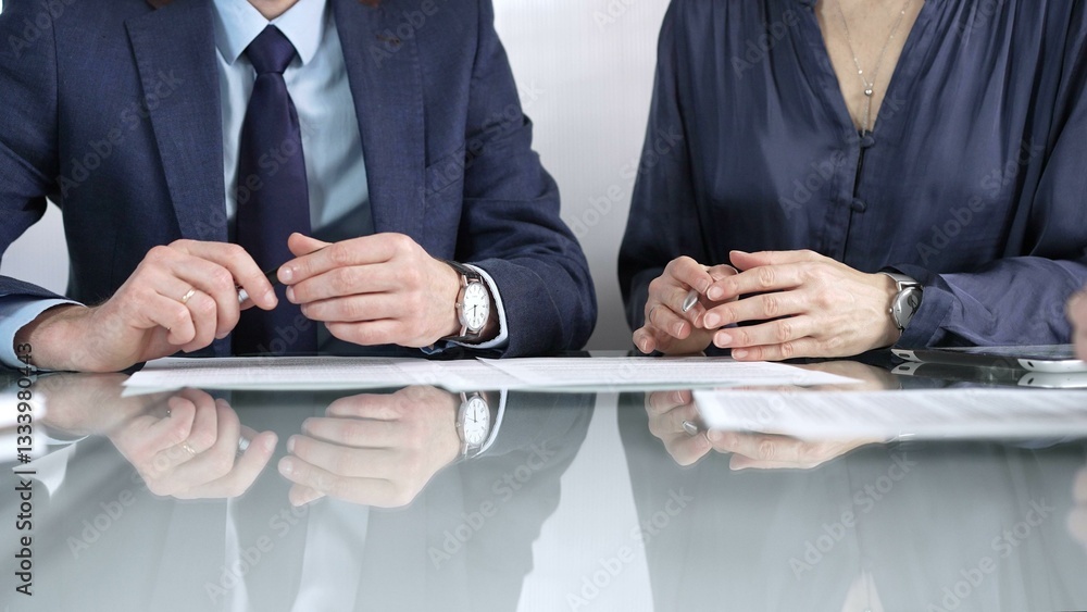 Business partners or lawyers are reviewing contract terms during a meeting, negotiating and making decisions together. Business people concept, close up view