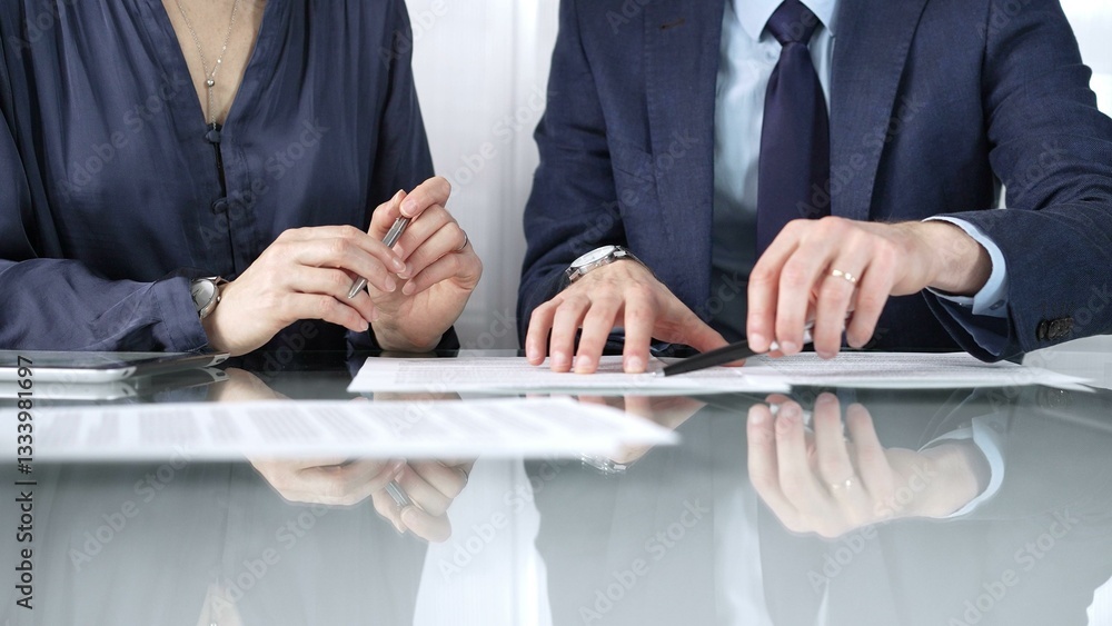 Business partners or lawyers are reviewing contract terms during a meeting, negotiating and making decisions together. Business people concept, close up view