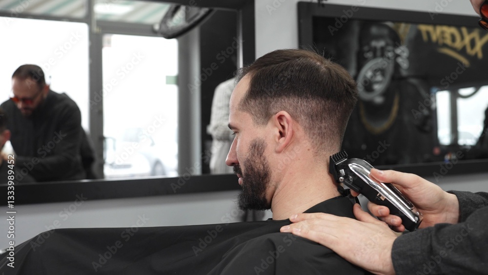 Skilled barber trimming client's hair using electric razor, creating contemporary hairstyle in modern barbershop setting with precise, professional technique