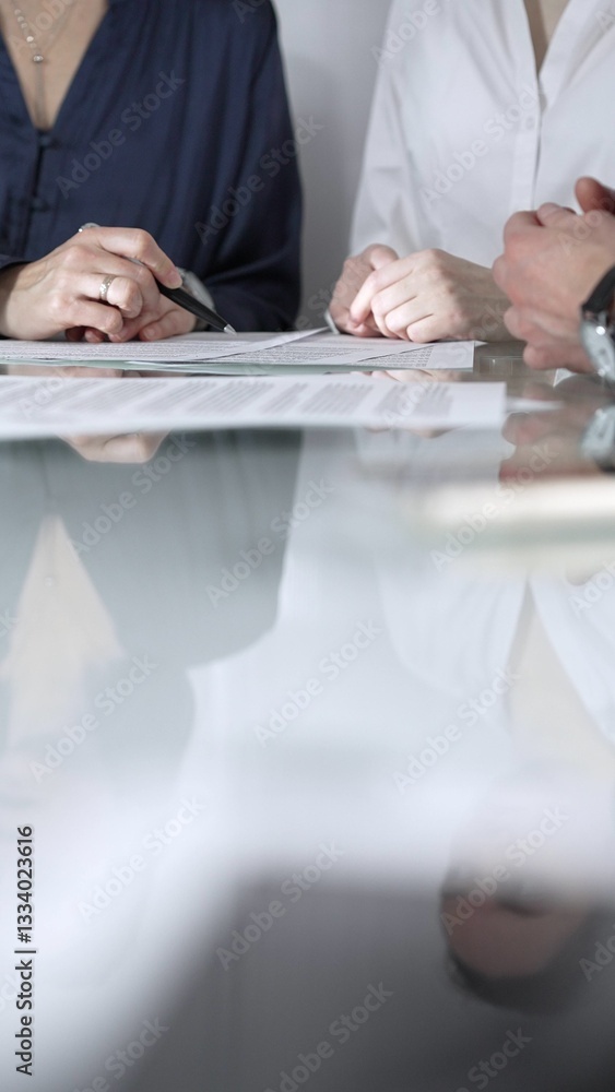 Business people are reviewing contract terms during a meeting, negotiating and making decisions together, vertical close up view. Copy space area