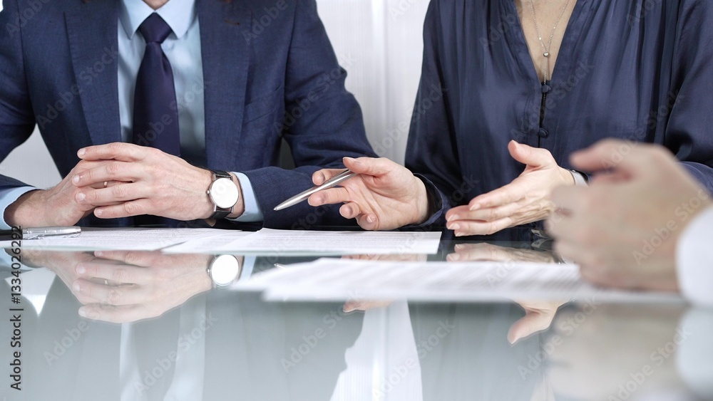 Business partners or lawyers are discussing contract papers during a meeting, negotiating and making decisions together. Business people concept, close up