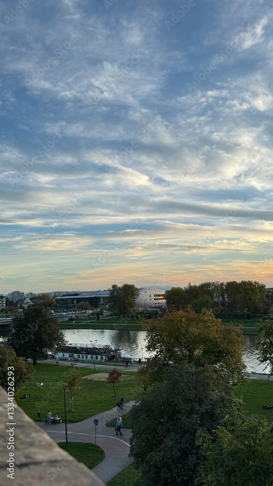 Obraz premium “Warm sunset view from Krakow castle overlooking river, buildings and calm nature.”