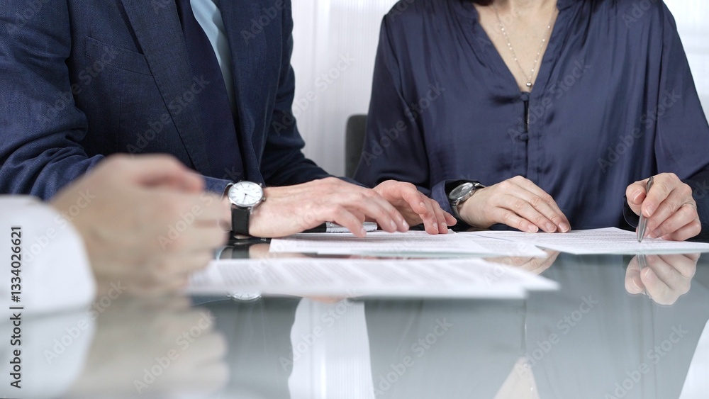 Business people reviewing contract terms while sitting at the glass desk during a meeting, negotiation in office, close up view. Success concept