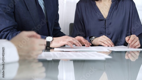 Obraz na płótnie Business people reviewing contract terms while sitting at the glass desk during a meeting, negotiation in office, close up view. Success concept w salonie
