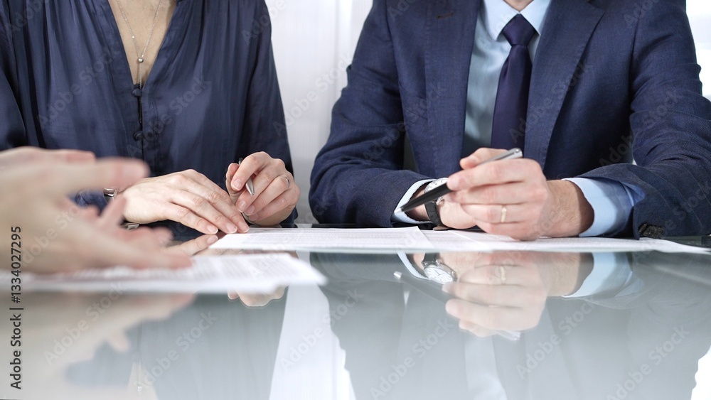 Business partners or lawyers are discussing contract papers during a meeting, negotiating and making decisions together. Business people concept, close up