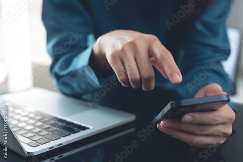 Sticker Business woman hand using mobile smart phone with laptop computer on office table, close up