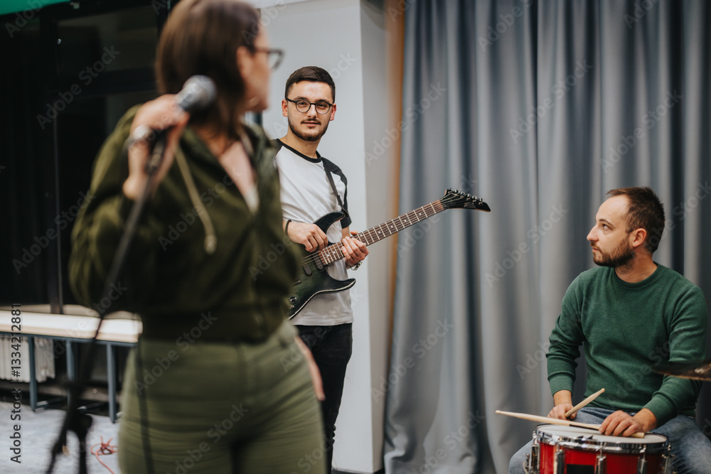 Obraz premium Three musicians collaborate during a band practice session, with each focusing on their respective instruments.