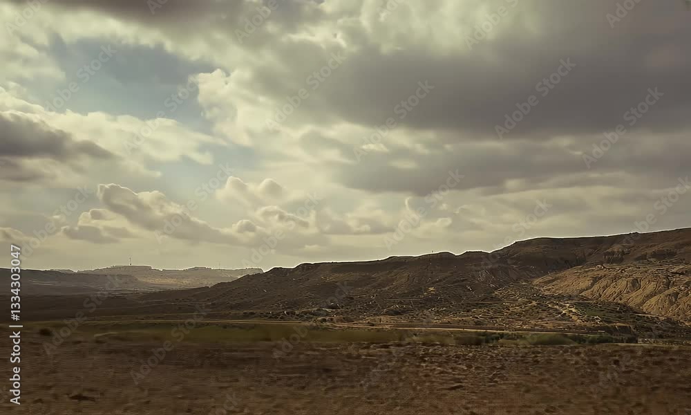Cloudy sky over arid valley landscape, distant hills and sparse vegetation, suitable for travel or environmental themes Cloudy sky over arid valley landscape, distant hills and sparse vegetation, suitable for travel or environmental themes
