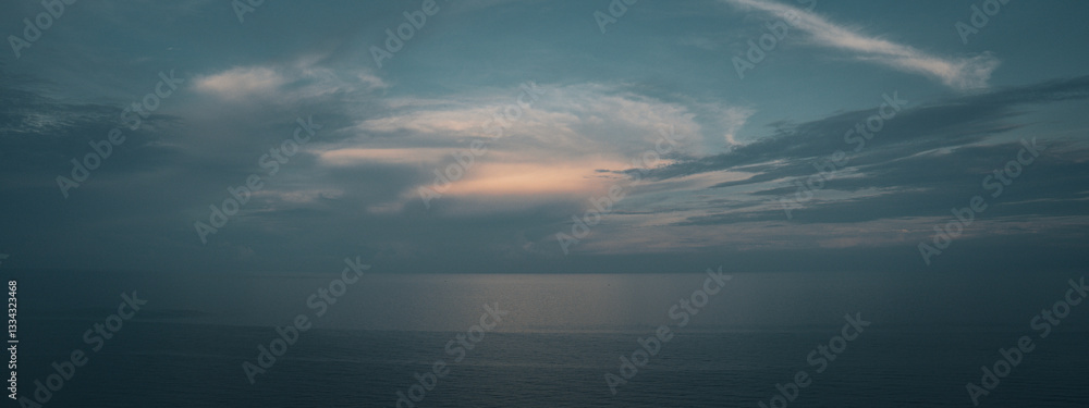 Obraz premium The blue sky in the early morning meets the calm, serene ocean, creating a tranquil, peaceful view. Soft light at dawn paints the horizon, making the sunrise an atmospheric, scenic skyscape of nature.