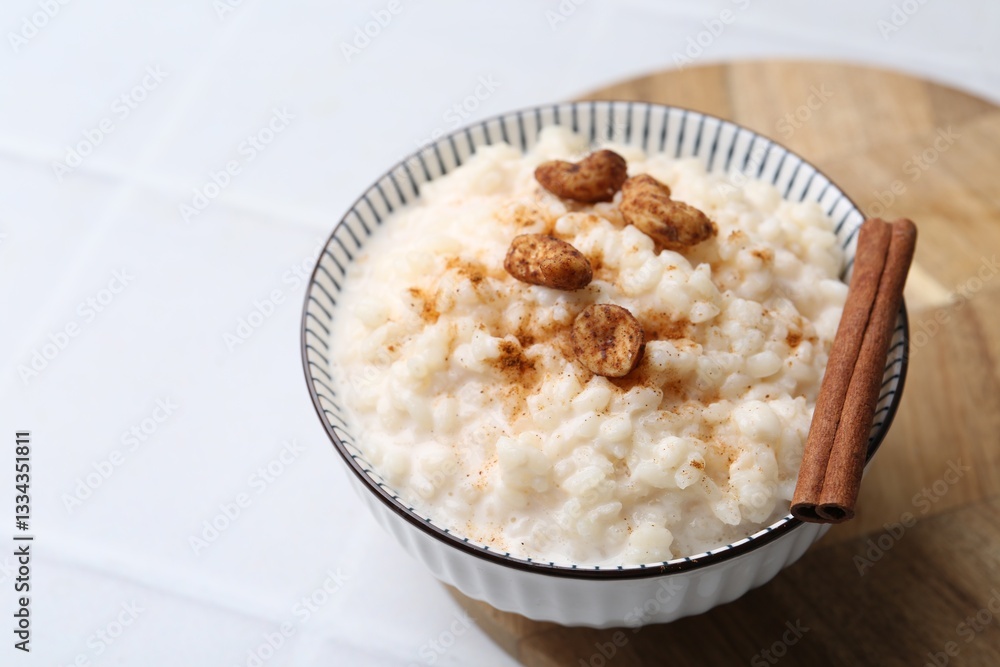 Delicious rice pudding with cinnamon and cashew nuts on white tiled table, closeup Delicious rice pudding with cinnamon and cashew nuts on white tiled table, closeup