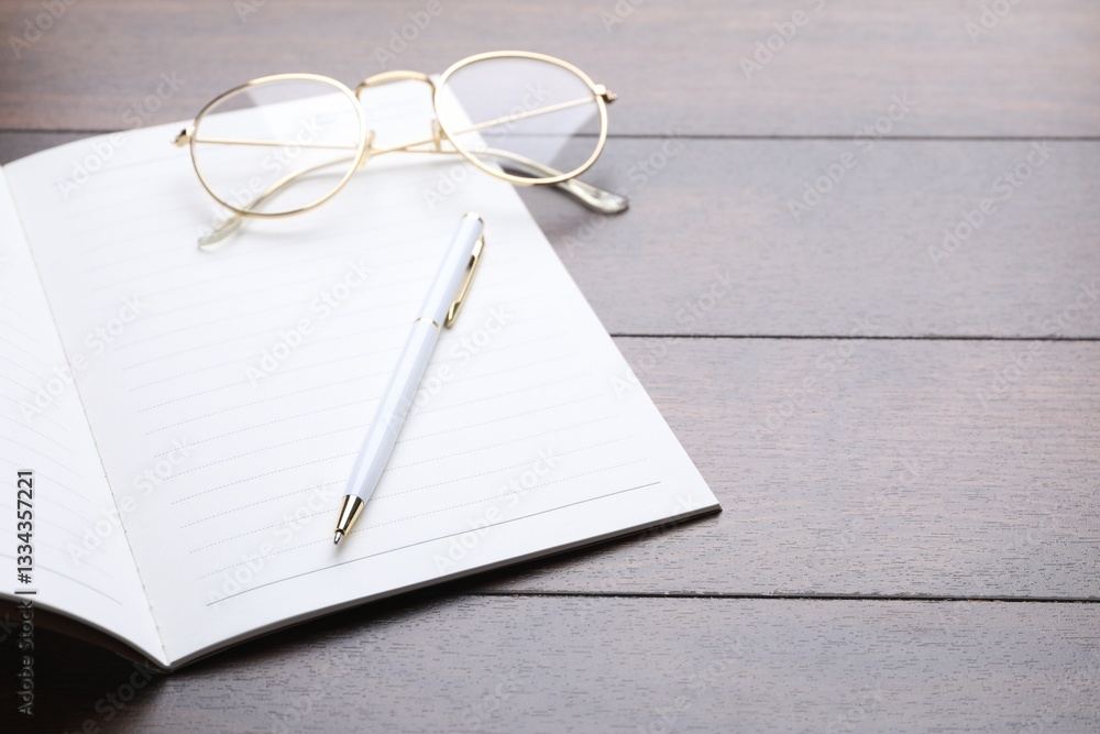 Open copybook, pen and glasses on wooden table, closeup. Space for text Open copybook, pen and glasses on wooden table, closeup. Space for text