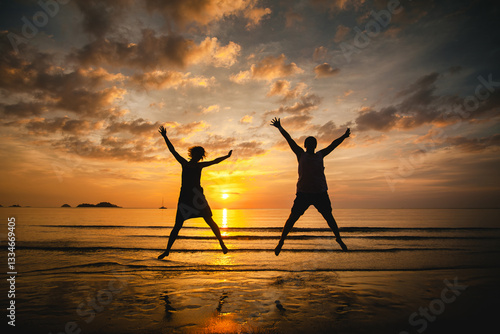 Obraz na płótnie Silhouettes of a man and woman, a joyful couple jumping together against a stunning sunset at the water's edge, capturing a moment of happiness and freedom. w salonie
