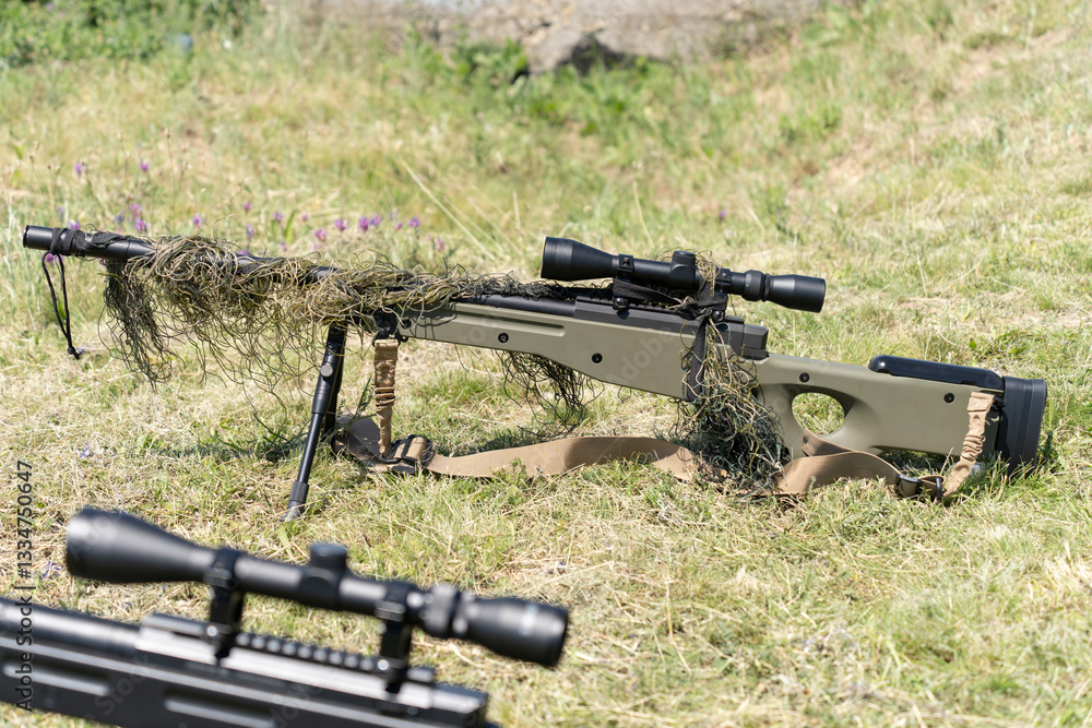 Sniper rifles with scopes on grassy field Sniper rifles with scopes on grassy field