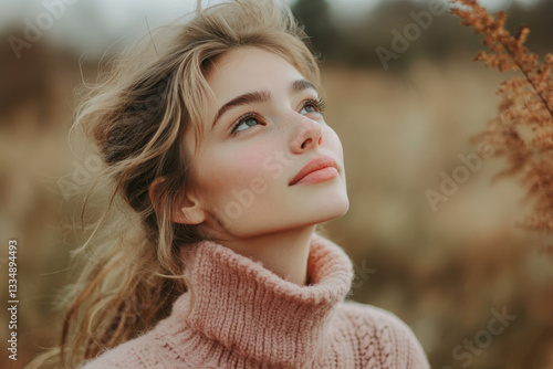Woman in pink sweater gazes at the sky, her long hair flowing, captivated by the beauty above.