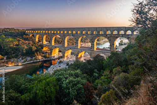 Pont du Gard, ancient Roman aqueduct bridge, elevated view, river bend and complete arches, early morning golden light, Gorges du Gardon, natural landscape, UNESCO Biosphere Reserve, Provence, France
